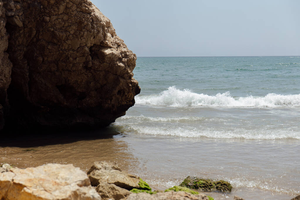 Вибіркове фокусування каменів з водоростями на узбережжі моря з синім небом на задньому плані в Каталонії (Іспанія).  - Фото, зображення