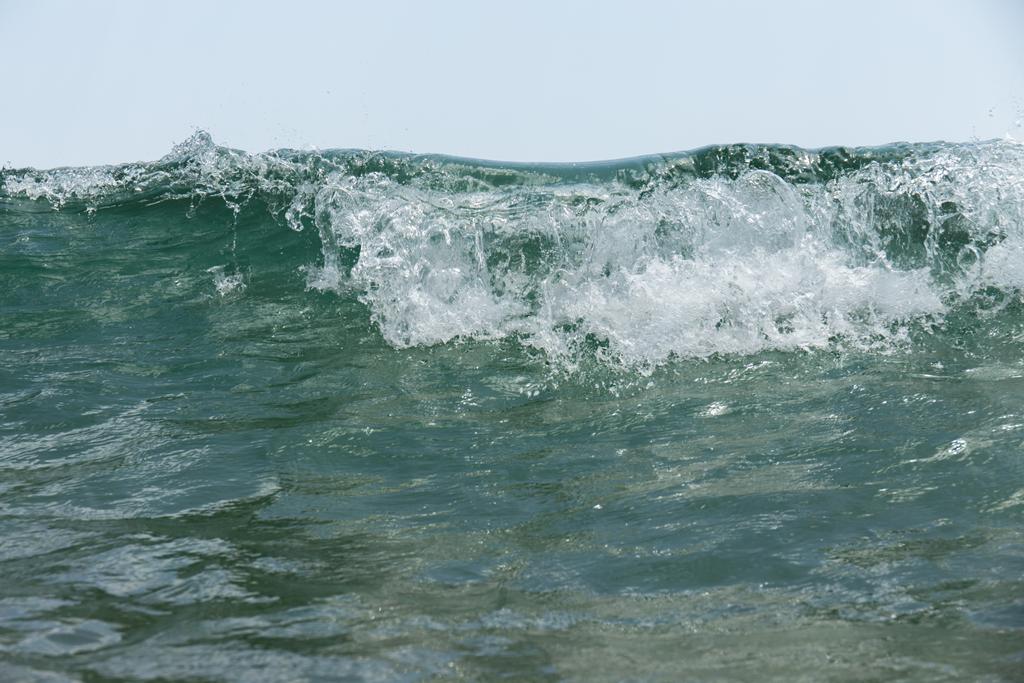 Vista de cerca de la ola de mar con espuma y cielo azul en el fondo
  - Foto, imagen