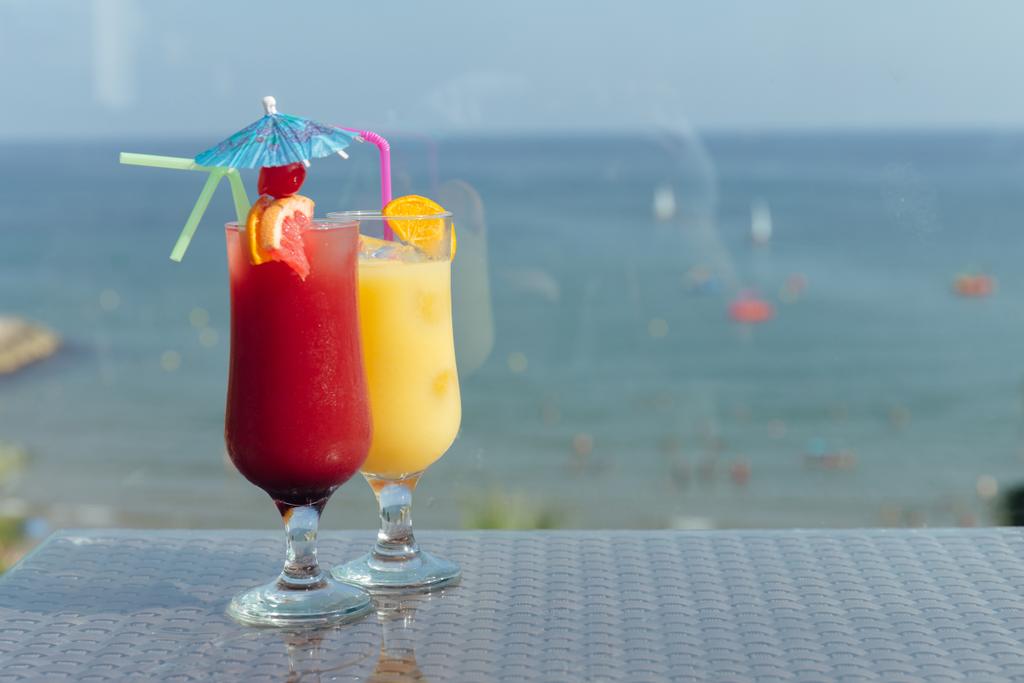 Glazen cocktails op tafel met zee en blauwe lucht op de achtergrond  - Foto, afbeelding