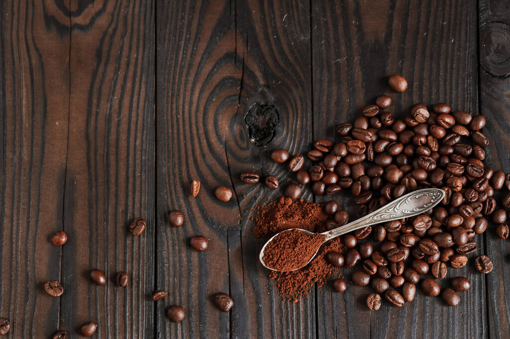 Paahdetut aromaattiset kahvipavut säkissä, jauhettu kahvi lusikassa, tummalla puupohjalla
 - Valokuva, kuva