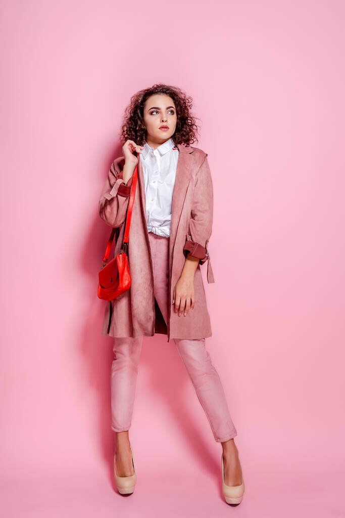 Νεαρή κομψή γυναίκα με μοντέρνο ροζ παλτό. απομονωμένη λήψη στούντιο - Φωτογραφία, εικόνα