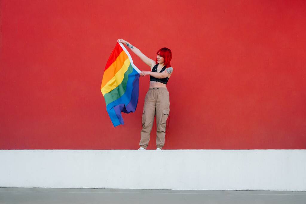 Kaunis laukaus naisen heiluttaen värikäs lippu punaisella taustalla - Valokuva, kuva