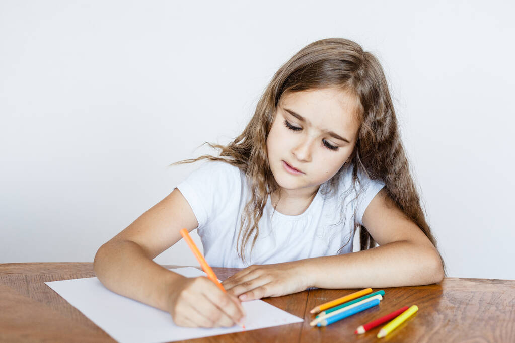 Το κορίτσι ζωγραφίζει σε ένα σημειωματάριο, γράφει γράμματα, χρωματιστά μολύβια, τάξεις στο σπίτι, online εκπαίδευση, ανάπτυξη της νοητικής νοημοσύνης - Φωτογραφία, εικόνα