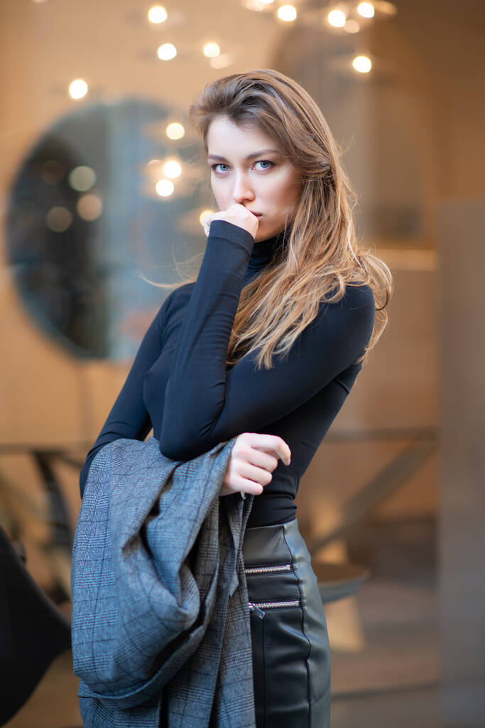 Joven mujer caucásica de moda vestida con ropa negraesposing al aire libre, Nochebuena. Hermosa chica caucásica en Milán, Italia. Moda callejera, vacaciones de invierno - Foto, imagen