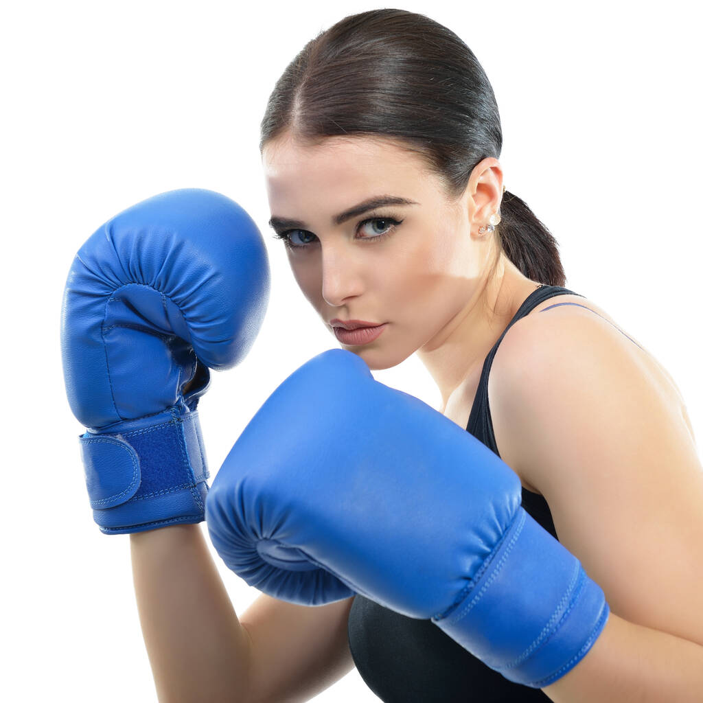 Sportowa dziewczyna robi ćwiczenia bokserskie. Zdjęcie młodej kobiety w rękawiczkach bokserskich odizolowanej na białym tle. Siła, motywacja, zdrowie i piękno. - Zdjęcie, obraz