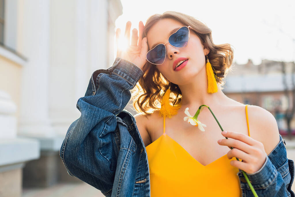 hermosa mujer sexy con estilo en vestido elegante amarillo con chaqueta de mezclilla, traje de moda, tendencia de moda primavera verano, sol, gafas de sol azules, moda callejera, estilo hipster, accesorios de moda - Foto, imagen