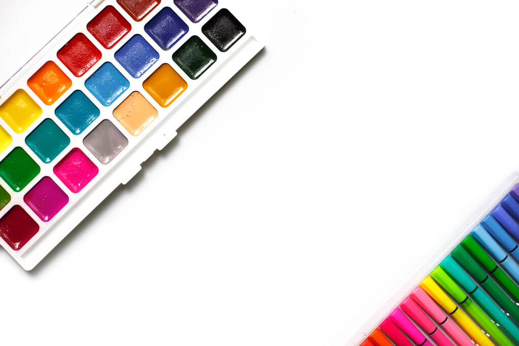 Eine Palette farbiger Aquarelle mit Pinseln und Markierungen auf weißem Hintergrund mit Platz für Text. Kreativ-Kurse mit Kindern zu Hause und in der Schule, Kunst-Meisterkurse, das Konzept der kreativen Entwicklung. Desktop der Kreativwerkstatt-Flatlay - Foto, Bild