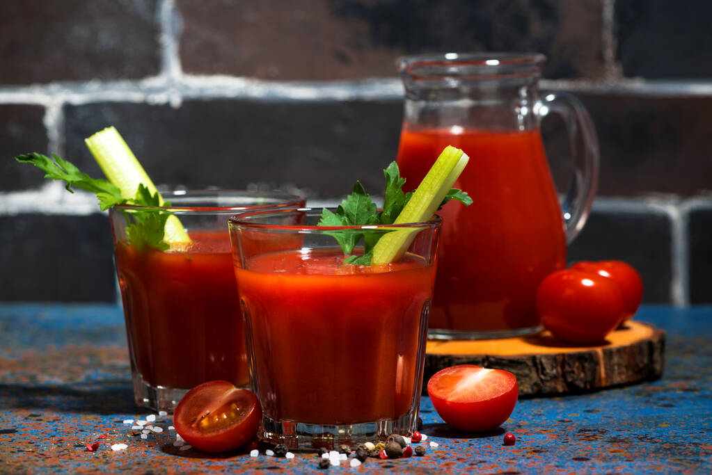 zumo de tomate fresco con sal y apio sobre mesa oscura, primer plano horizontal
 - Foto, Imagen