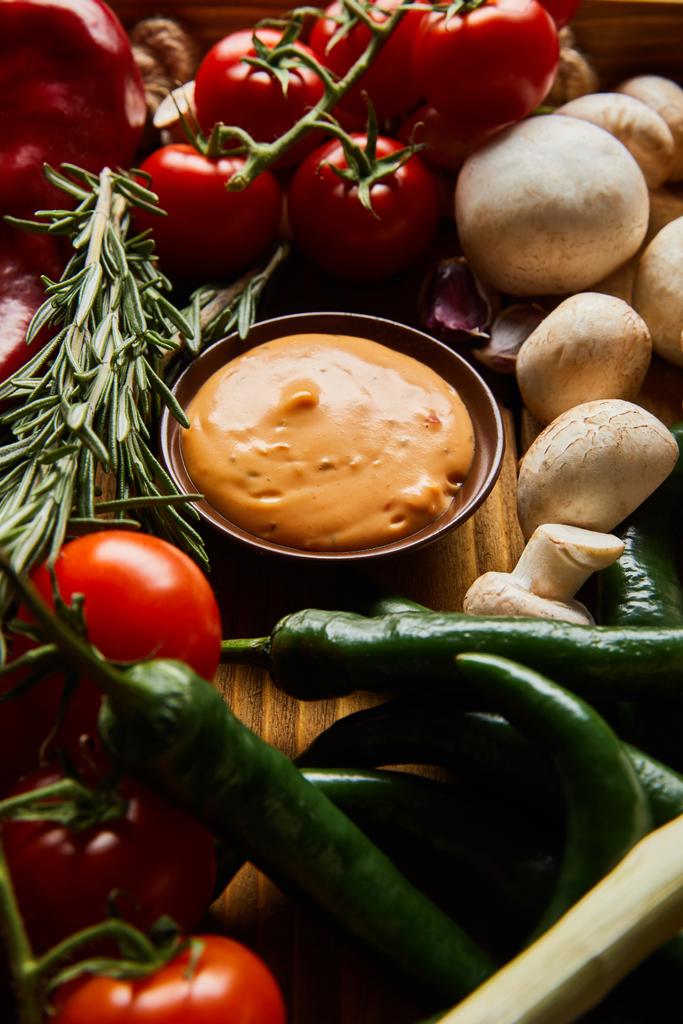вкусный соус в миске рядом со свежими зрелыми овощами
  - Фото, изображение