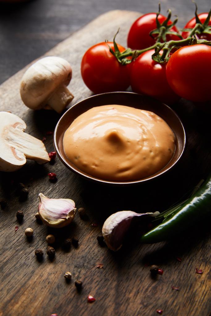 délicieuse sauce dans un bol près des champignons, tomates et épices sur planche de bois
 - Photo, image