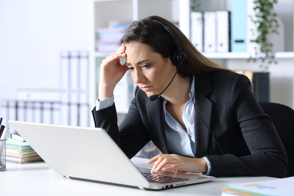 Triste telemarketer mujer leyendo malas noticias en el portátil sentado en un escritorio en la oficina
 - Foto, Imagen