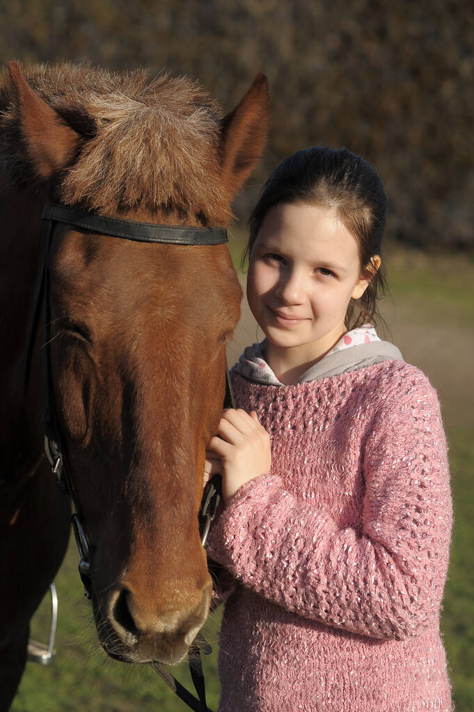 fiatal lány mellett a feje egy barna ló - Fotó, kép