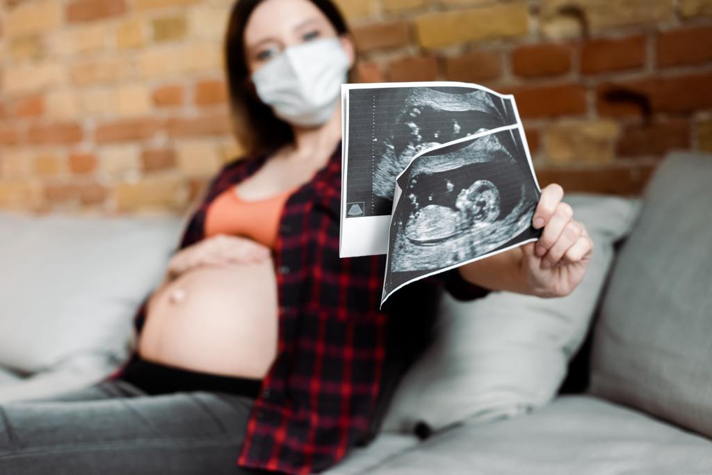 selective focus of pregnant woman in medical mask holding ultrasound photos  - Photo, Image