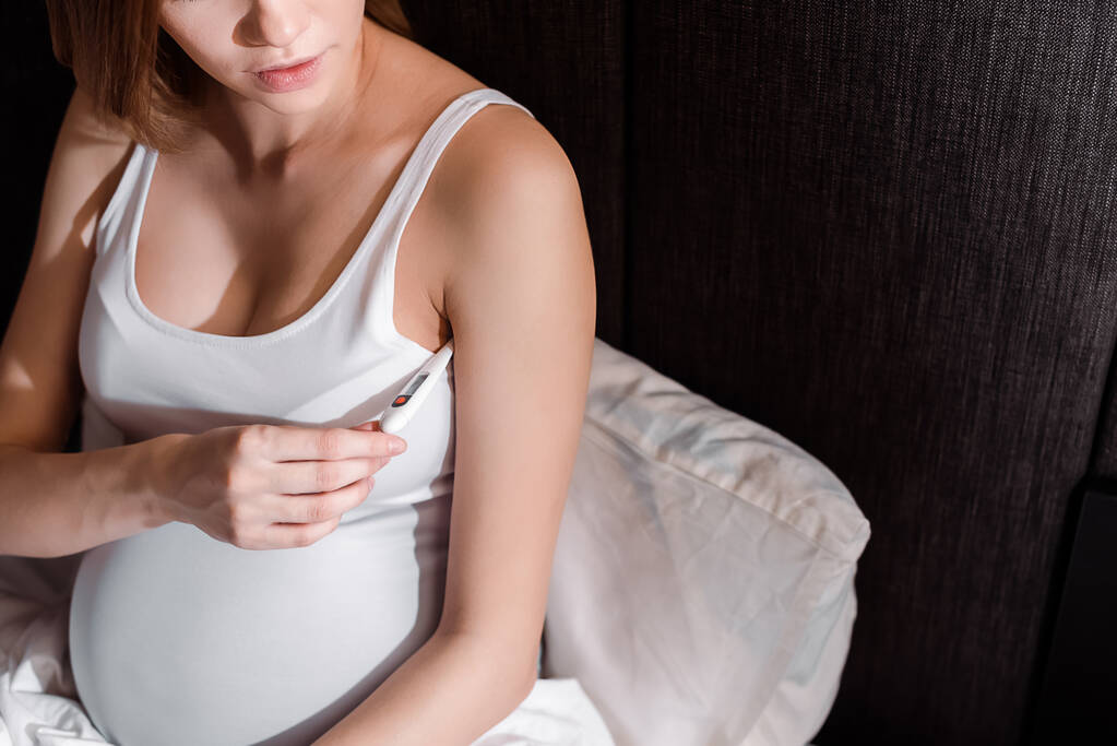 Hasta hamile bir kadının yatak odasında dijital termometre tutması.  - Fotoğraf, Görsel