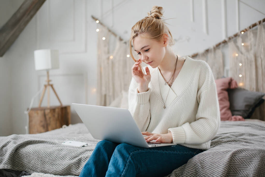 Dziewczyna student nauka online z nauczycielem skype, szczęśliwa młoda kobieta patrzeć na laptopa siedzieć na łóżku w domu. - Zdjęcie, obraz