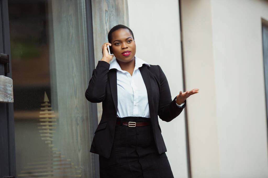 Афроамериканська бізнес-леді в офісі посміхається, виглядає впевненою і щасливою, успішною - Фото, зображення