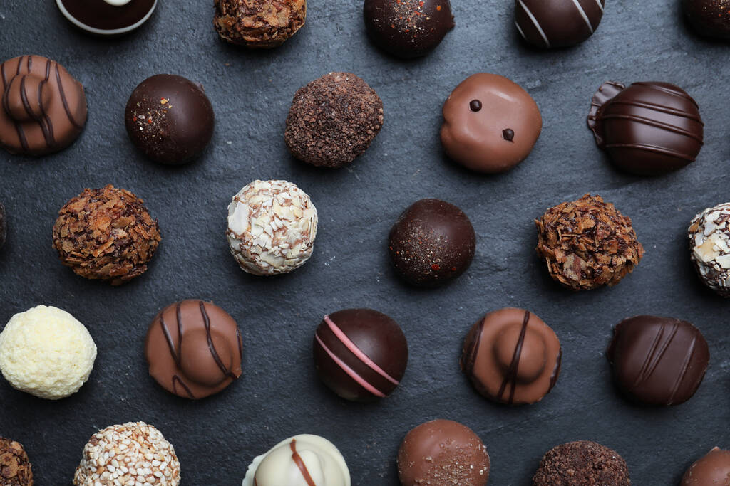 Různé lahodné čokoládové bonbóny na černém stole, byt ležel - Fotografie, Obrázek
