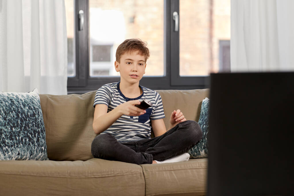 хлопчик з дистанційним керуванням дивиться телевізор вдома
 - Фото, зображення