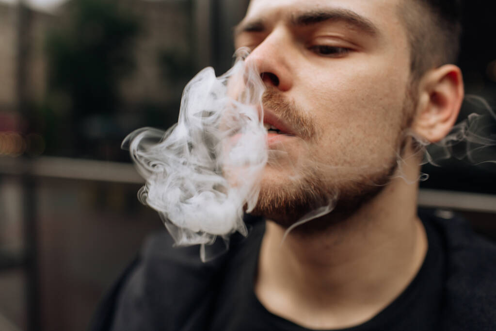 O homem fuma um cigarro. A propagação da fumaça do cigarro. bigode
 - Foto, Imagem