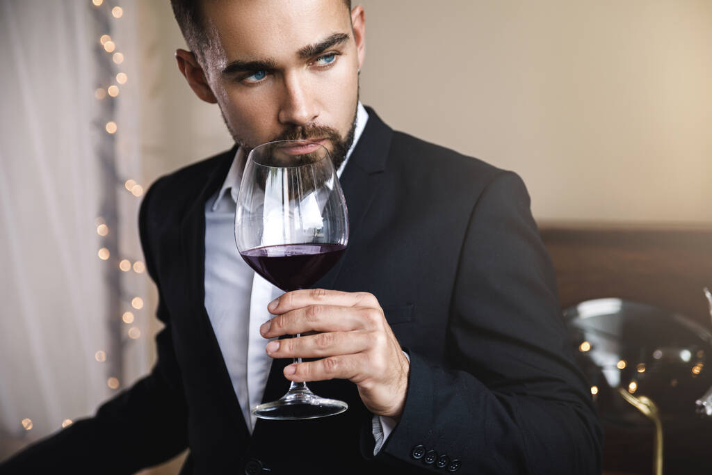 Πορτρέτο του όμορφου γενειοφόρου άνδρα με ένα ποτήρι κόκκινο κρασί - Φωτογραφία, εικόνα