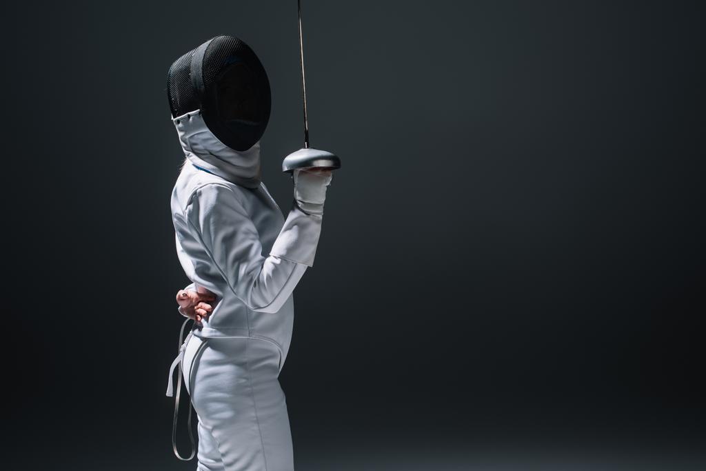 Side view of fencer holding rapier isolated on black with copy space - Photo, Image
