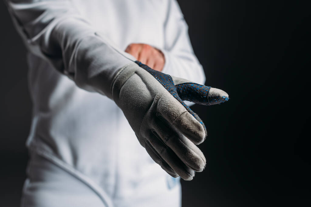 Widok szermierki zakładającej rękawiczki izolowane na czarno  - Zdjęcie, obraz