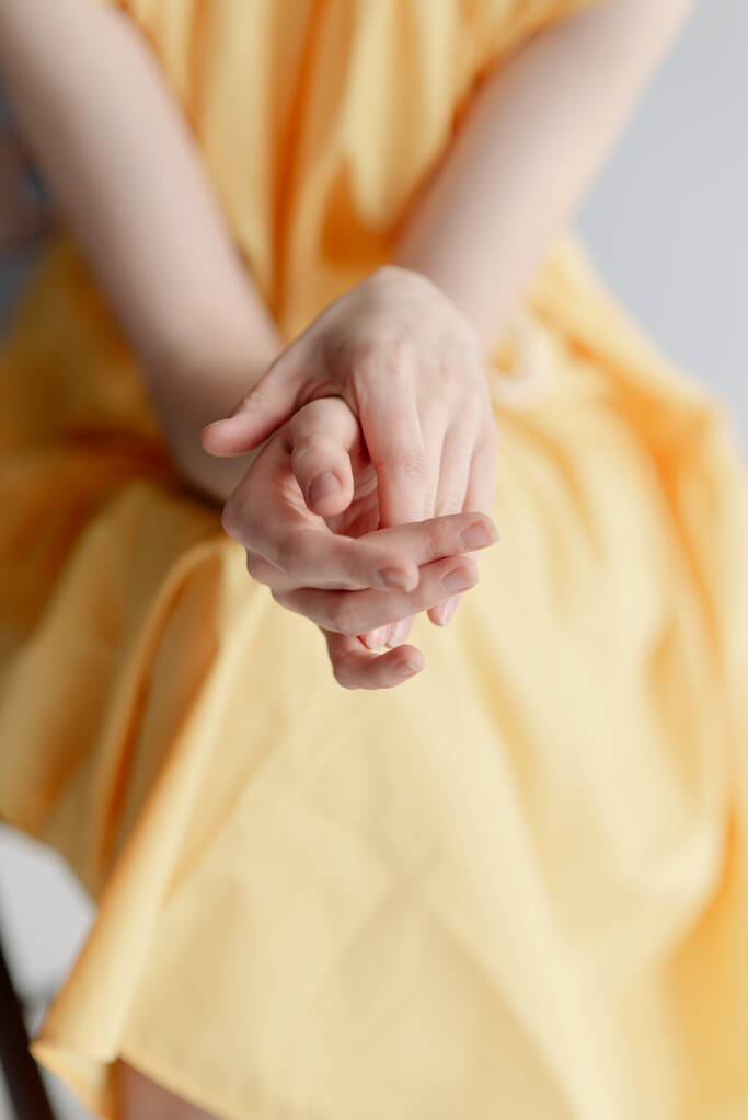 As mãos magras de uma jovem. Menina em um vestido amarelo
  - Foto, Imagem