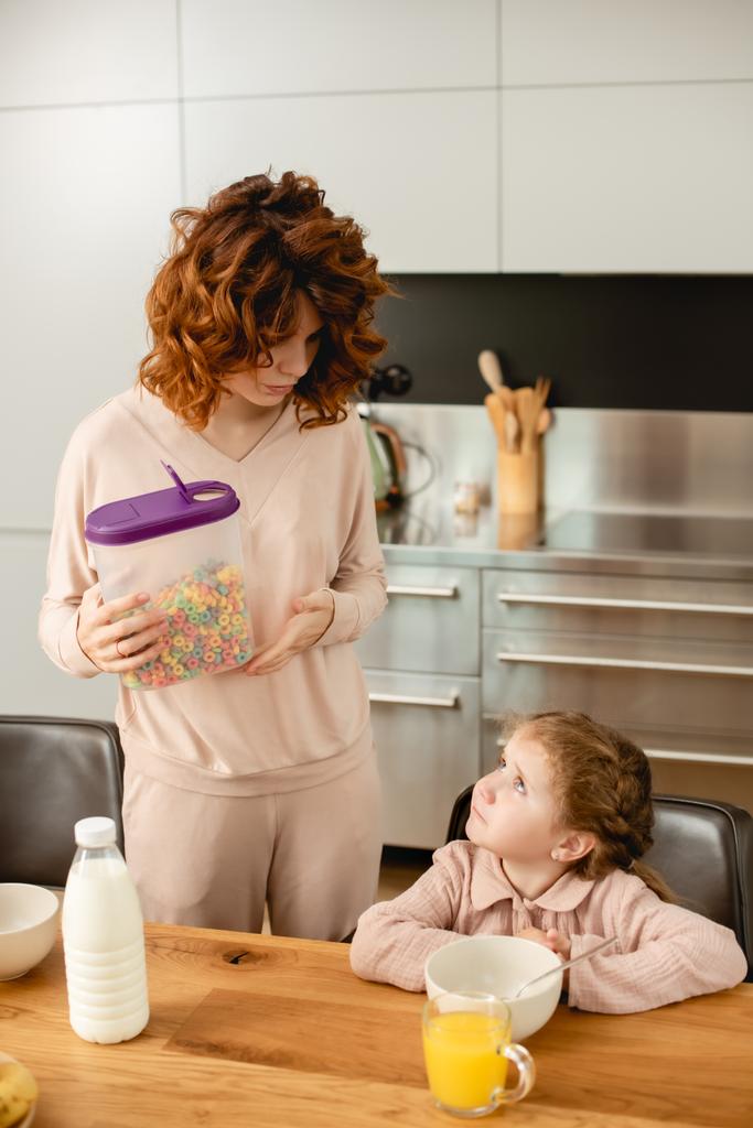 carino bambino guardando madre tenendo contenitore con fiocchi di mais
  - Foto, immagini