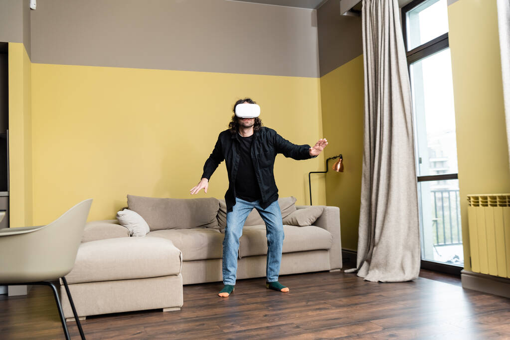 Man in virtual reality headset staande in de woonkamer - Foto, afbeelding
