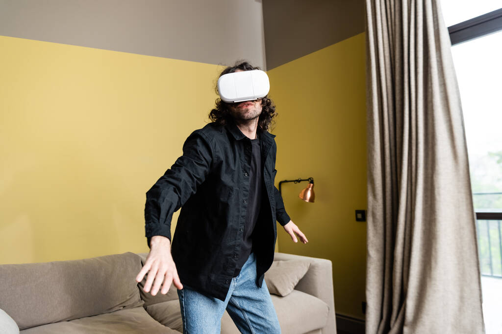 Curly mies pelaa videopeli vr kuulokkeet kotona
  - Valokuva, kuva