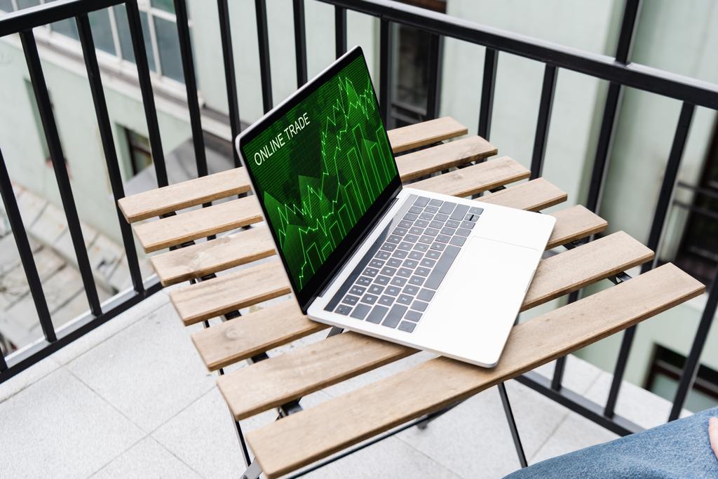 Vista ritagliata dell'uomo seduto vicino al computer portatile con sito web commerciale online sul balcone
  - Foto, immagini