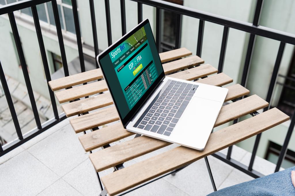 Widok przycięty laptopa ze stroną zakładów sportowych i człowieka siedzącego na balkonie  - Zdjęcie, obraz