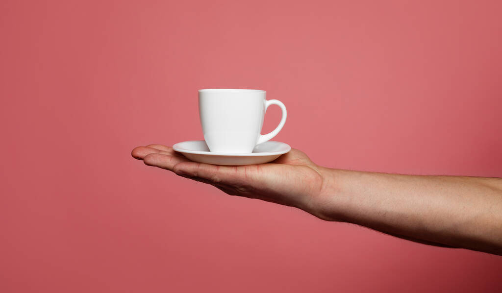 Een kop koffie. Close-up foto van een kop koffie in de hand van een man. - Foto, afbeelding