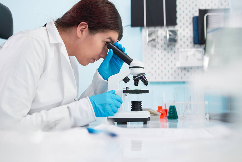 Samičí epidemioložka se dívá pod mikroskop v laboratoři. - Fotografie, Obrázek