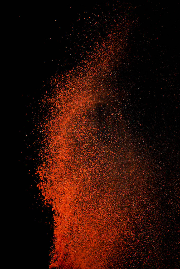 Red paprika spices powder explosion, flying chili pepper isolated on black background. Splash of spice background.  - Photo, Image