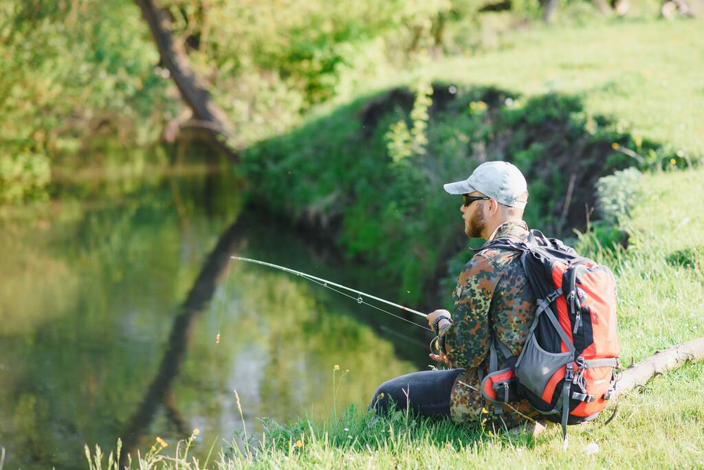 Nuori kalastaja kalastaa lähellä jokea. Ulkoilun ja kalastuksen käsite
 - Valokuva, kuva