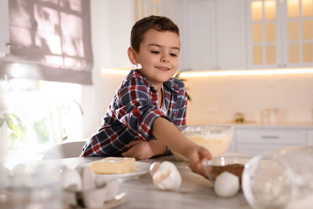 Милий маленький хлопчик готує тісто на кухні вдома
 - Фото, зображення