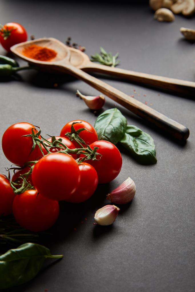 organik kiraz domatesleri, sarımsak karanfilleri, kırmızı biber tozu ve yeşil fesleğen yapraklı ahşap kaşıklar. - Fotoğraf, Görsel