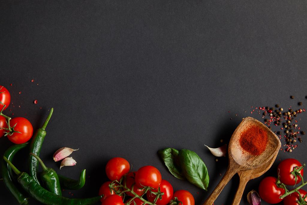 vista superior de tomates cereja maduros, dentes de alho, alecrim fresco, pimenta, folhas de manjericão e pimentas verdes em preto
 - Foto, Imagem