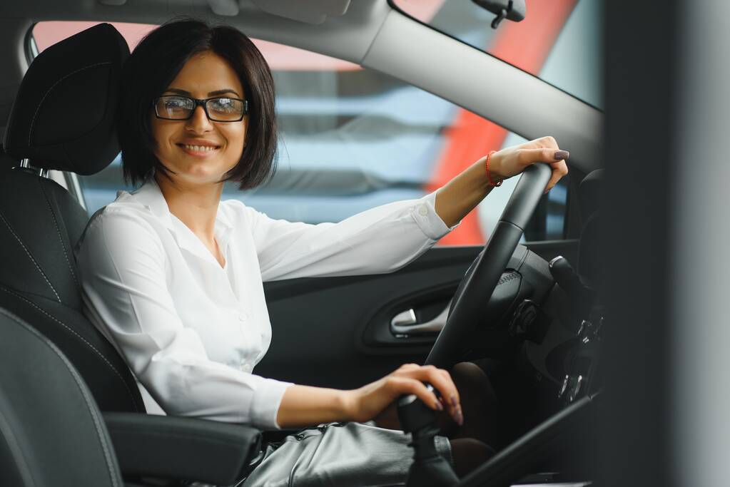 Fénykép egy boldog fiatal nőről, aki az új kocsijában ül. Az autókölcsönzés koncepciója - Fotó, kép