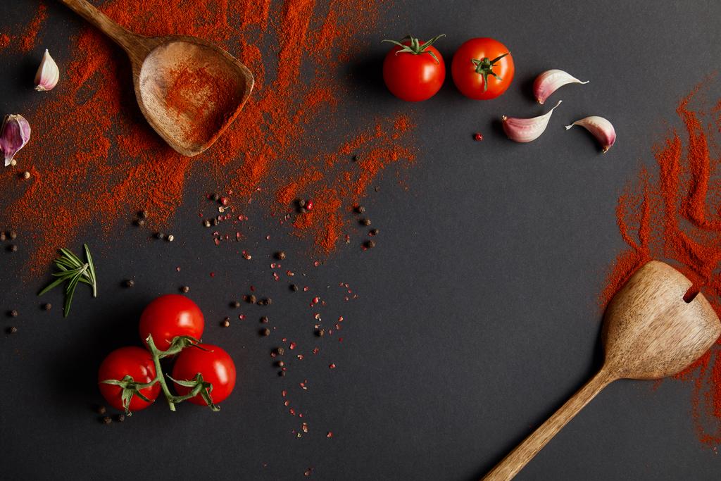 vista superior de sabrosos tomates cherry y hierbas frescas cerca de cucharas con pimentón en polvo sobre negro
  - Foto, Imagen