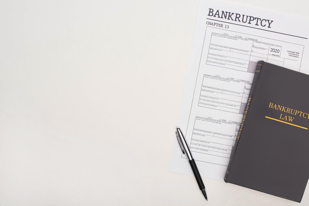 vista superior del papel de bancarrota, lápiz y libro de leyes sobre fondo blanco
 - Foto, Imagen