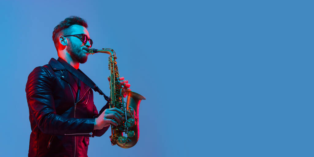 Jovem músico de jazz caucasiano tocando o saxofone em luz de néon, panfleto
 - Foto, Imagem