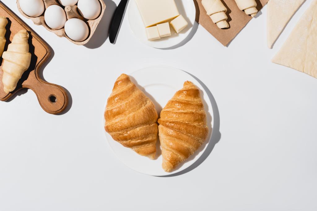 Draufsicht auf leckere gebackene Croissants auf Teller auf weißem Hintergrund - Foto, Bild