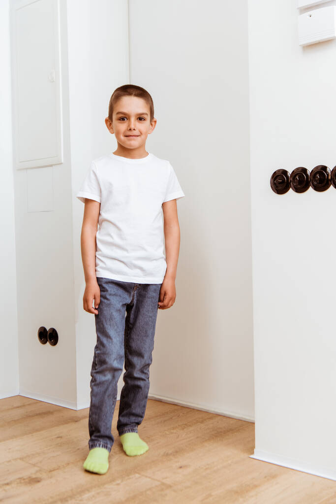 Sonriente niño mirando a la cámara mientras está de pie en el pasillo en casa
  - Foto, imagen