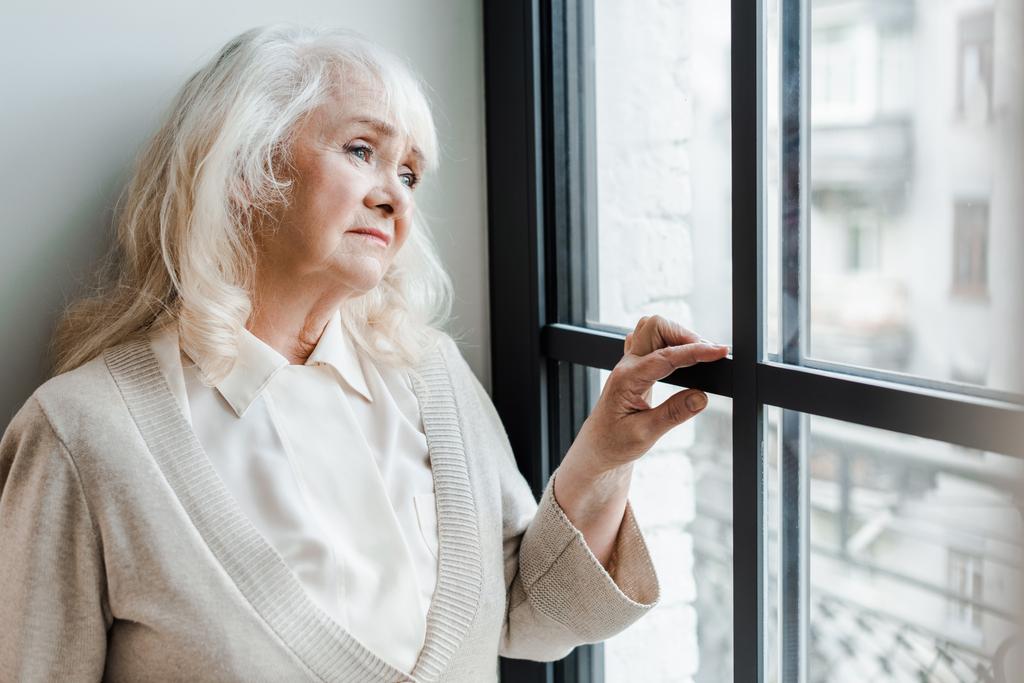 triste mulher idosa olhando através da janela durante o auto-isolamento
 - Foto, Imagem