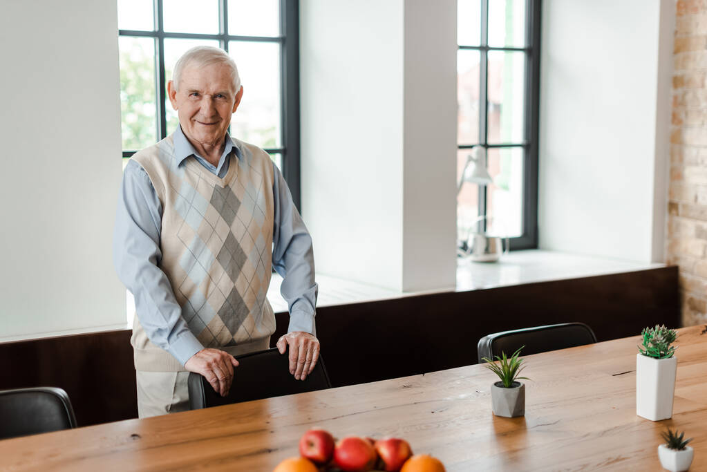 heureux homme âgé debout à table avec des fruits et des plantes pendant l'isolement personnel
  - Photo, image