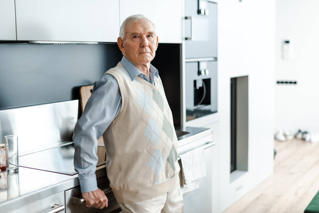 szomorú idős férfi áll a konyhában az önzárkózottság alatt  - Fotó, kép
