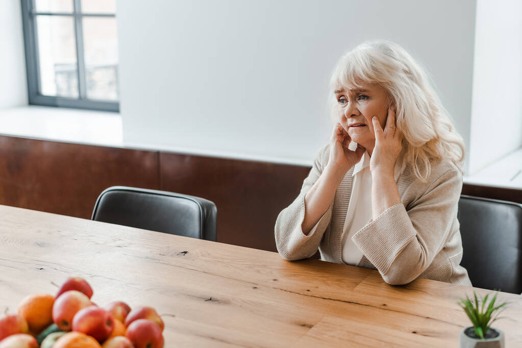 triste mulher idosa solitária sentada à mesa com frutas durante a quarentena
 - Foto, Imagem