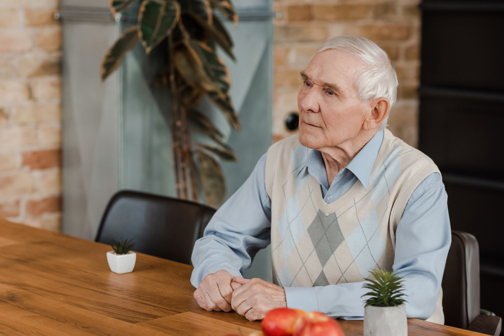 ηλικιωμένος μοναχικός άνθρωπος με φρούτα και φυτά στο τραπέζι κατά τη διάρκεια της απομόνωσης  - Φωτογραφία, εικόνα